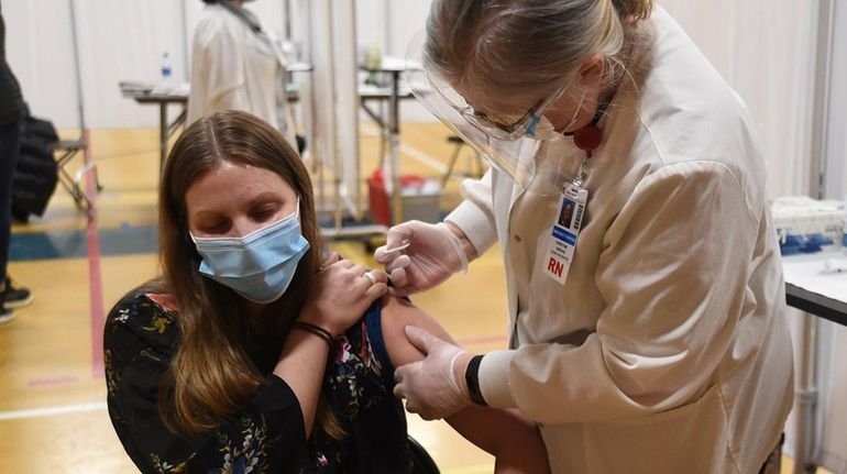 Andrea Reimond-nee, of Amityville, gets a COVID-19 shot from nurse Joanne...