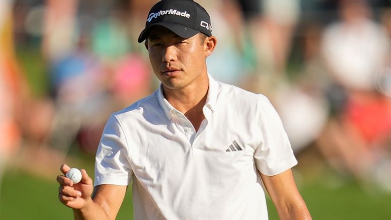 Collin Morikawa waves after making a putt on the 18th...