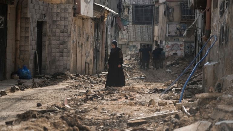 Palestinians walk on a damaged road following an Israeli military...