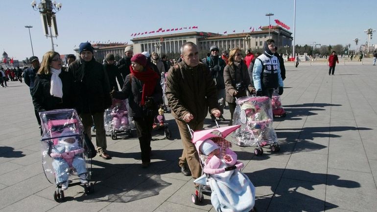 FILE- Spanish couples take their newly adopted Chinese children for...