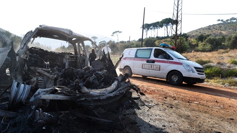 An ambulance drives past a vehicle that burned in the...