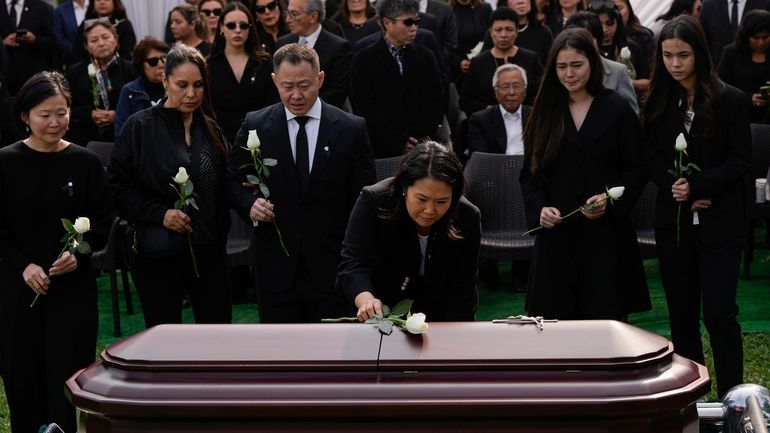 Keiko Fujimori places a flower over the coffin of her...