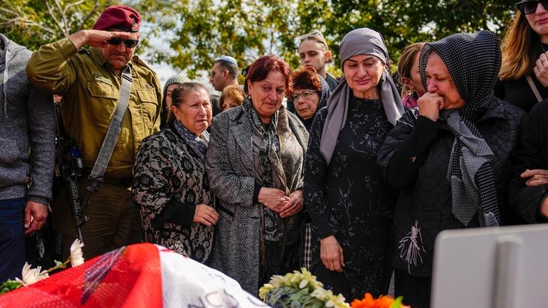 Mourners gather in grief around the grave of Staff sergeant...