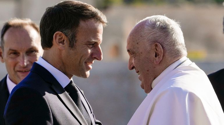 Pope Francis is welcomed by French President Emmanuel Macron as...