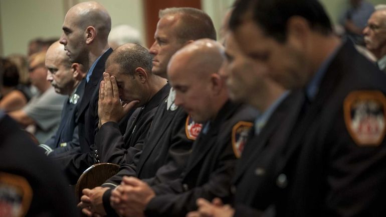 FDNY members pause at a memorial service at St. Brendan...