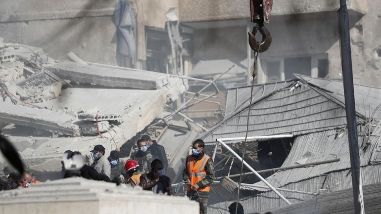 Emergency services work at a building hit by an air...