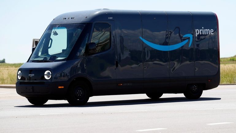 FILE- An driver drives a Rivian electric van as packages...