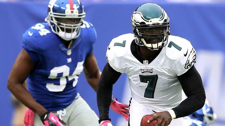 Philadelphia Eagles quarterback Michael Vick scrambles as Mathias Kiwanuka chases...