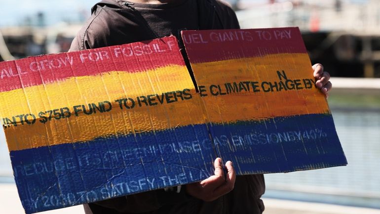 A demonstrator attends a news conference on the Climate Change Superfund...