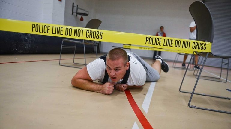 Raymond Ellis, 17, of Riverhead, crawls under police tape during...