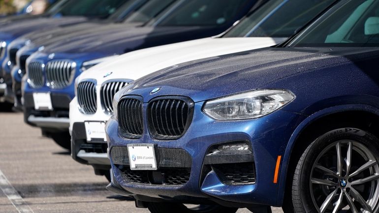 A long row of unsold 2021 X3 sports-utility vehicles sits...