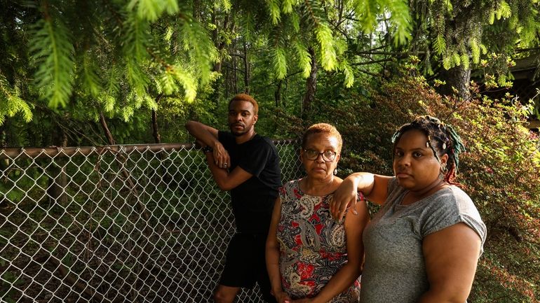 Pam Doughty, flanked by son Andre and daughter Jessica, in her backyard that backs...