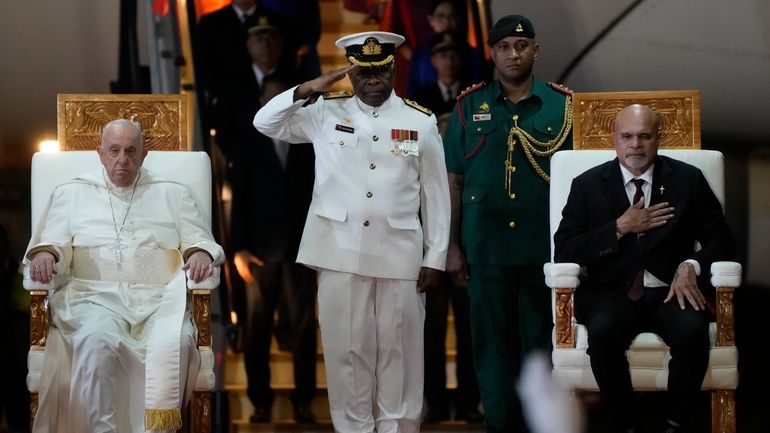 Pope Francis, left, is welcomed by Papua New Guinea's deputy...