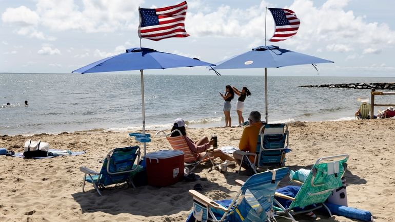 People fly the American flag on their beach umbrellas, Friday,...