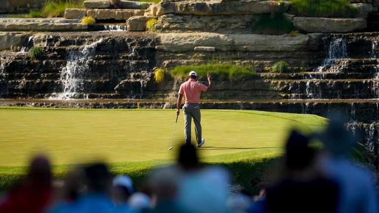 Tiger Woods waves after making a putt on the 13th...