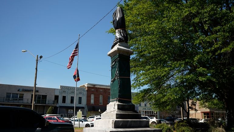 A weather-worn tarp covers the century-old Confederate monument in Grenada,...