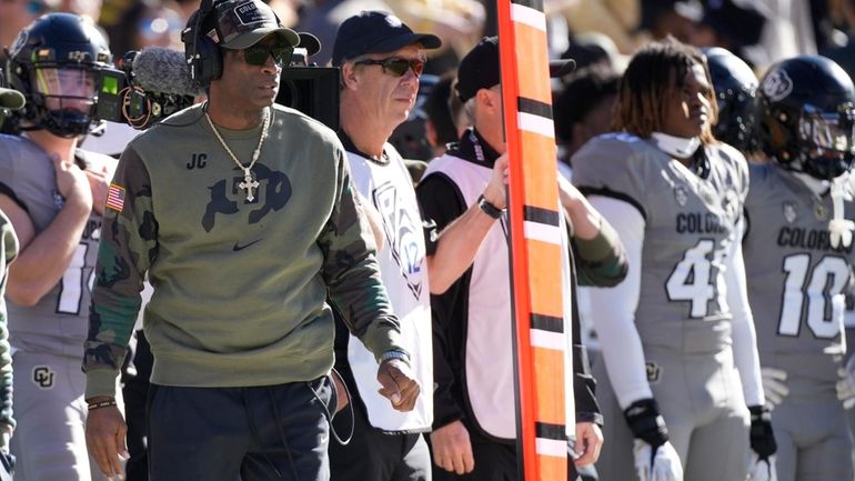 Colorado head coach Deion Sanders, left, looks on in the...