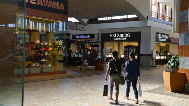 Shoppers stroll through the center of the Smith Haven Mall,...