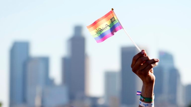 A pride flag is waved against the downtown Los Angeles...