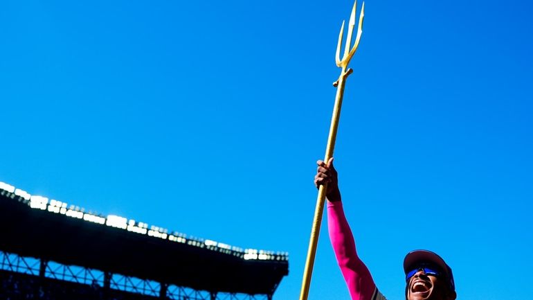 Seattle Mariners' Julio Rodríguez lifts a trident after a postgame...