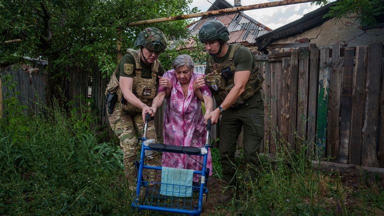 Police officers of the White Angels unit help an elderly...