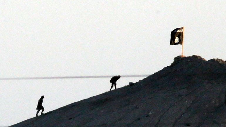 Militants with the Islamic State group are seen from the...