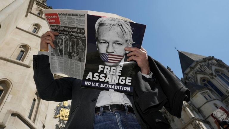 A protester reads a newspaper outside the High Court in...