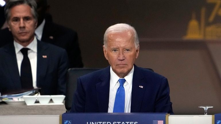 President Joe Biden sits as Secretary of State Antony Blinken,...