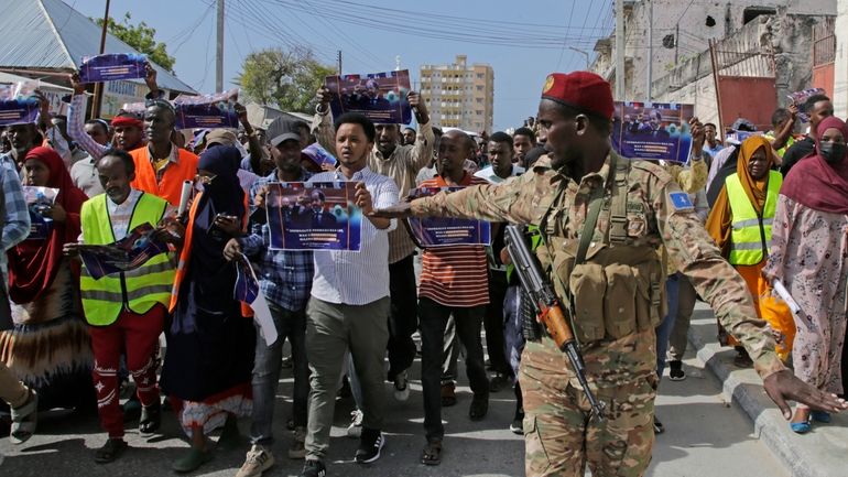 A Somali soldier controls the crowd as thousands of people...