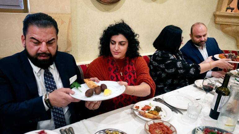 Sophia Armen, center passes a dish to Dr. Armond Aghakhanian...