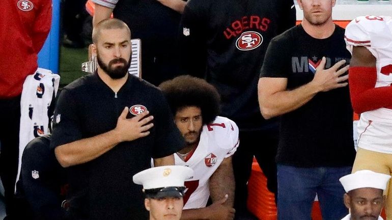 San Francisco 49ers quarterback Colin Kaepernick, middle, sits during the...