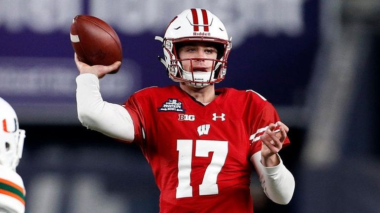 Wisconsin quarterback Jack Coan passes under pressure from Miami defensive...