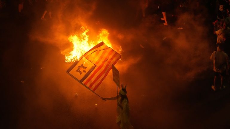 A demonstrator waves the Israeli and U.S. flags during a...