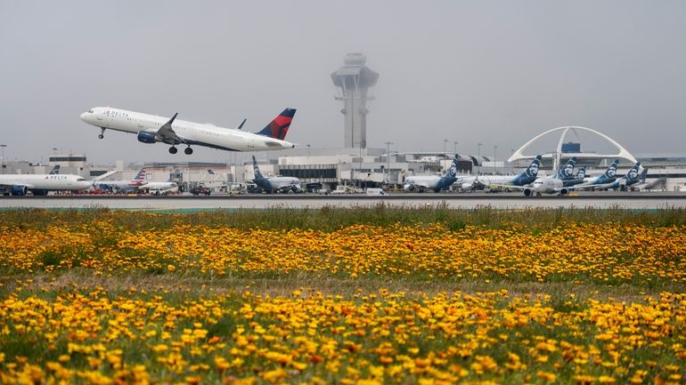 Flowers bloom along the runways as a Delta Airlines jet...