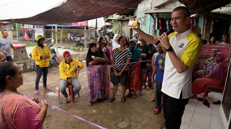 Rian Ernest, a Golkar Party candidate, shows his campaign cards...