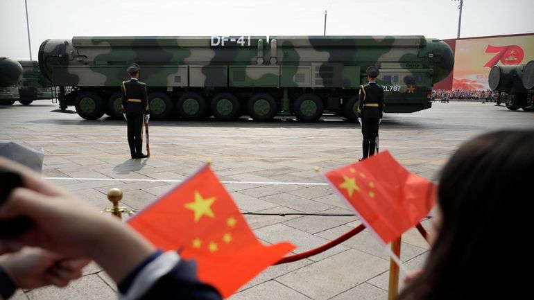 Spectators wave Chinese flags as military vehicles carrying DF-41 nuclear...