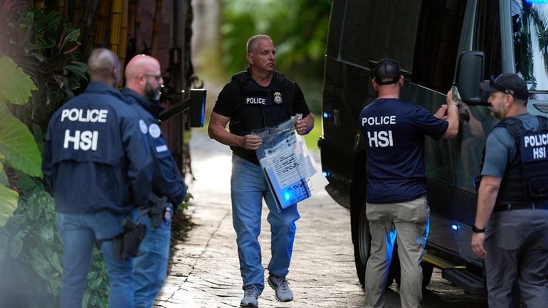 A law enforcement agent carries a bag of evidence to...