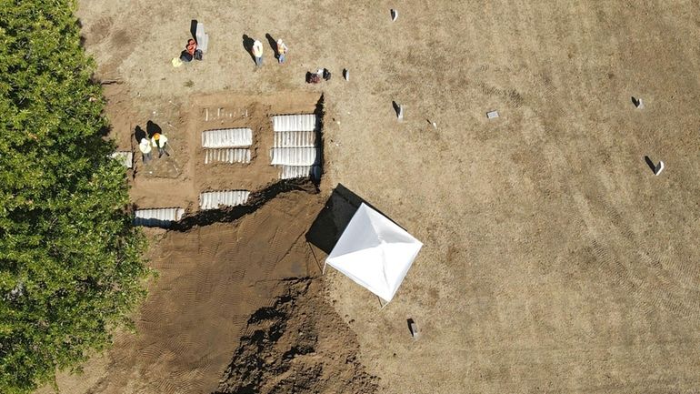 Crews work at Oaklawn Cemetery during an excavation while searching...