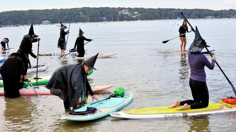 Paddleboard yoga enthusiasts particpate in the witches' paddle at Steer's...