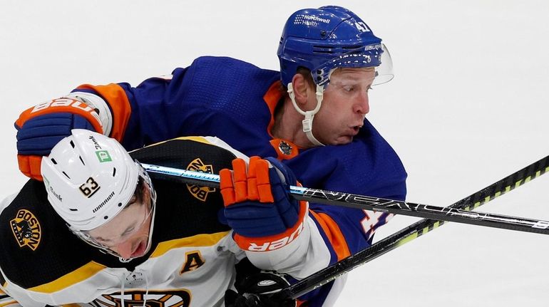 Leo Komarov of the Islanders skates against Brad Marchand of the...