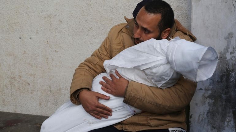 A Palestinian holds his child killed