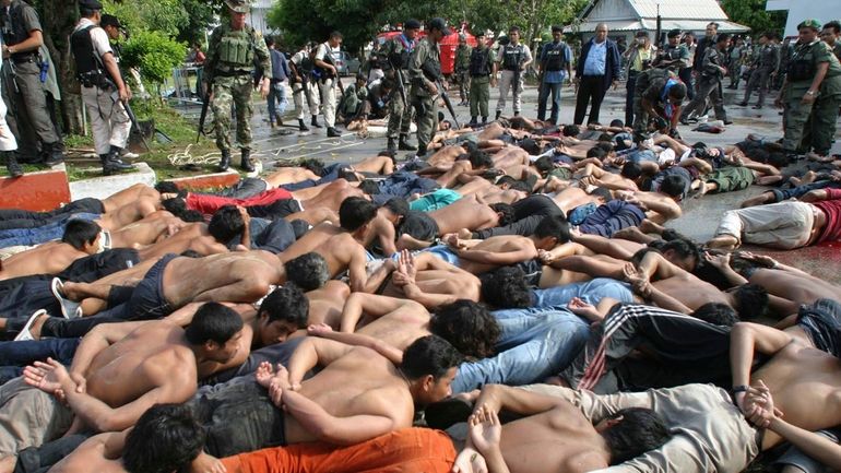 Thai-Muslim rioters lie on the ground after they were arrested...