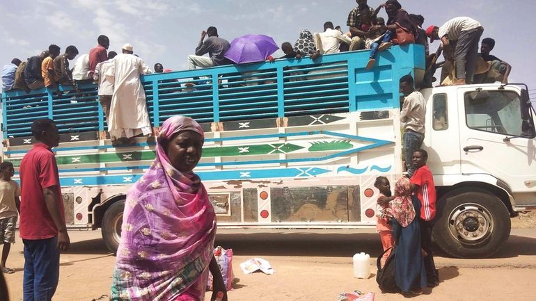 People board a truck as they leave Khartoum, Sudan, on...