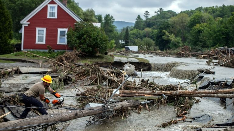 Zac Drown, of Lyndon Electric Company, clears debris amid flood...