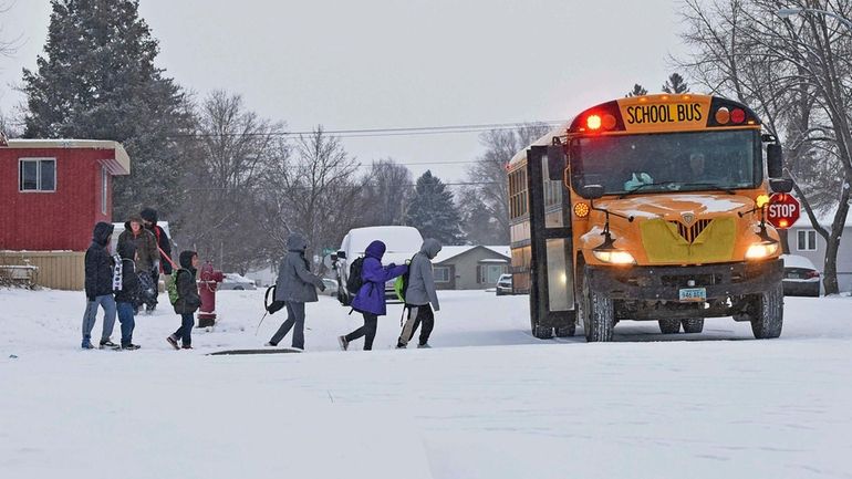 Children in winter coats line up to get into a...