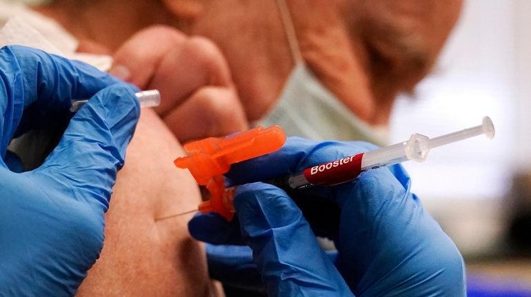 Pharmacist injects Robert Champion, of Lawrence, Mass., with a booster...