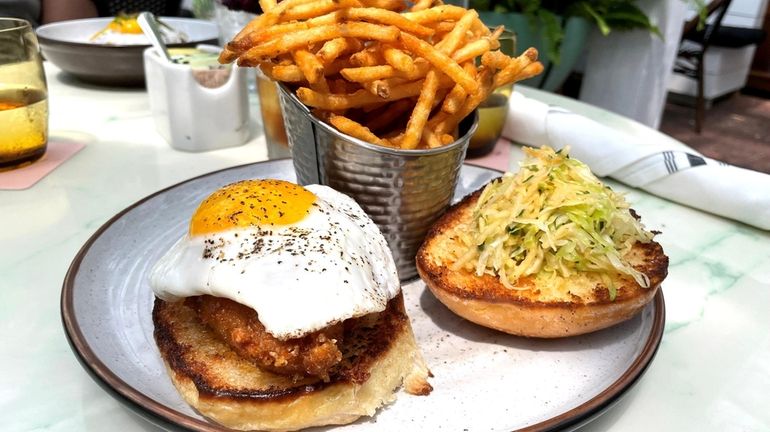 A chicken sandwich topped with fried egg at American Beech,...