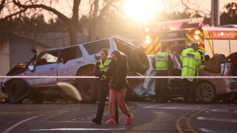 A police officer comforts a woman at a crash site...