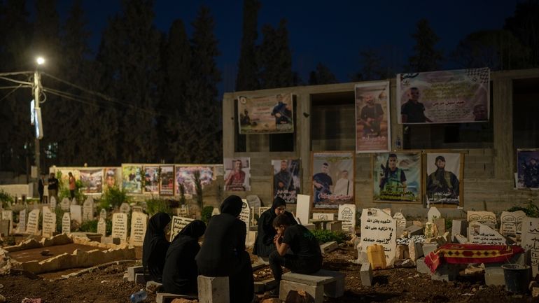 Family members sit next to the grave of Odei, 22,...