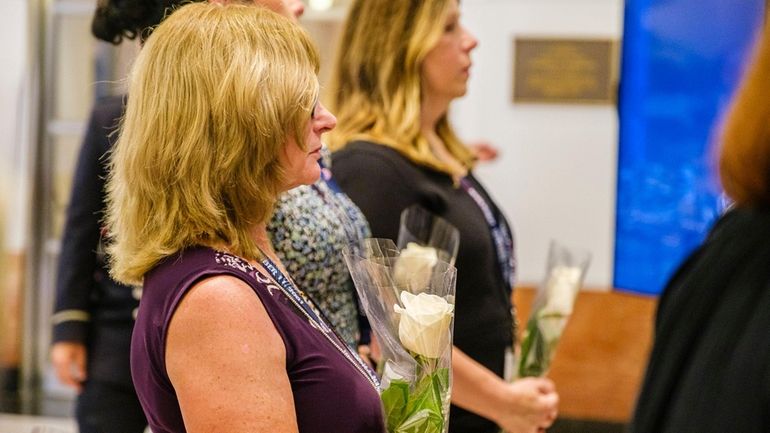 Family members step forward to place white roses on a...